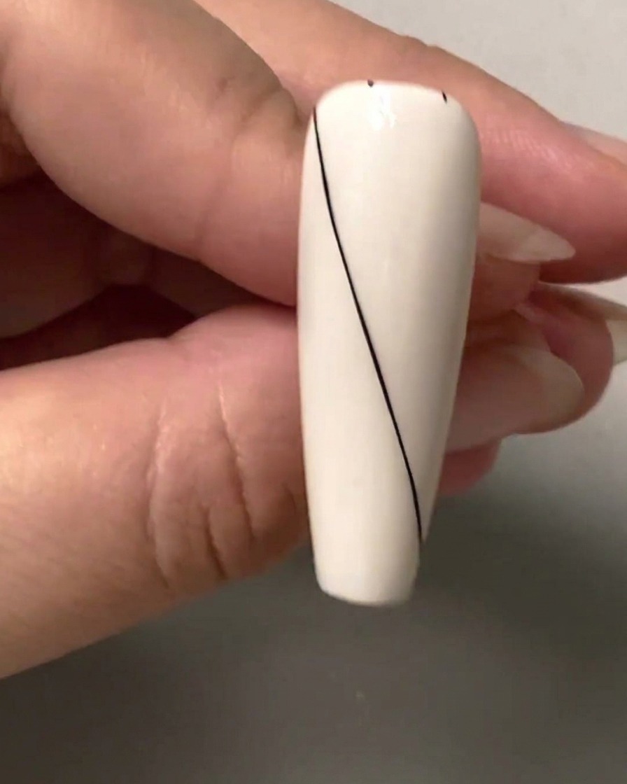 Primo piano di ununghia che mostra piccoli punti di spaziatura neri contrassegnati lungo la sezione vuota superiore destra.