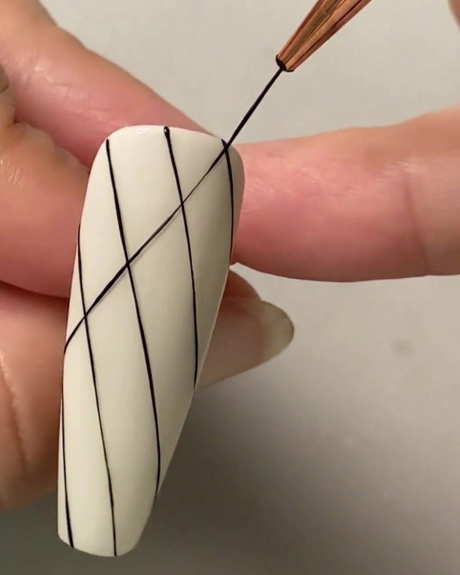 Un pennello liner sottile che disegna una linea diagonale nera che si interseca attraverso le linee parallele esistenti per formare un motivo a griglia di rombi.