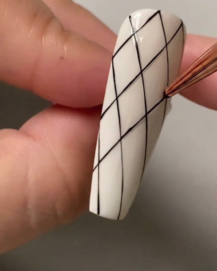 Primo piano di un pennello liner che segna punti di spaziatura sulla sezione superiore dellunghia.