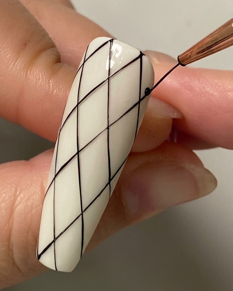 Primo piano di un pennello liner che disegna una linea diagonale di intersezione sulla metà inferiore dellunghia.