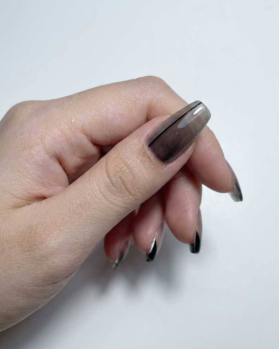 Una mano che mostra unghie con sfumature fumè e french finish completate con un top coat ad alta lucidità.