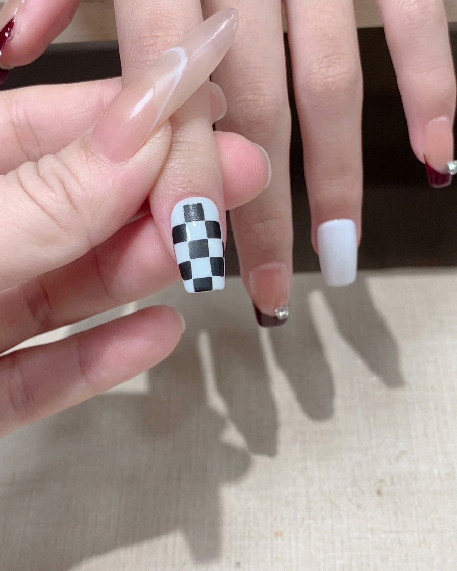 Un pennello che applica un top coat lucido sul design a scacchi bianco e nero completato.