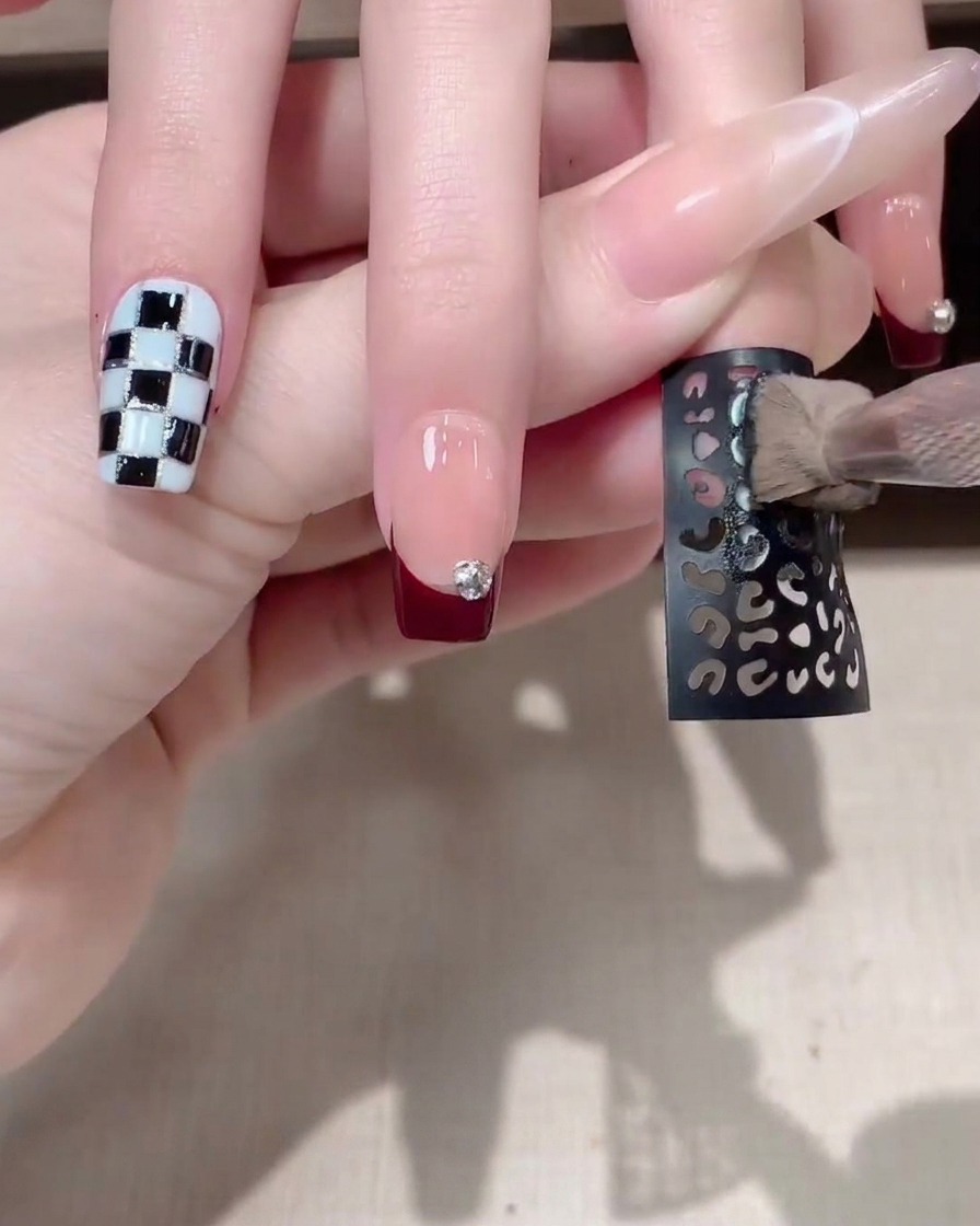 Uno stencil adesivo decorativo scuro applicato su ununghia con manicure.
