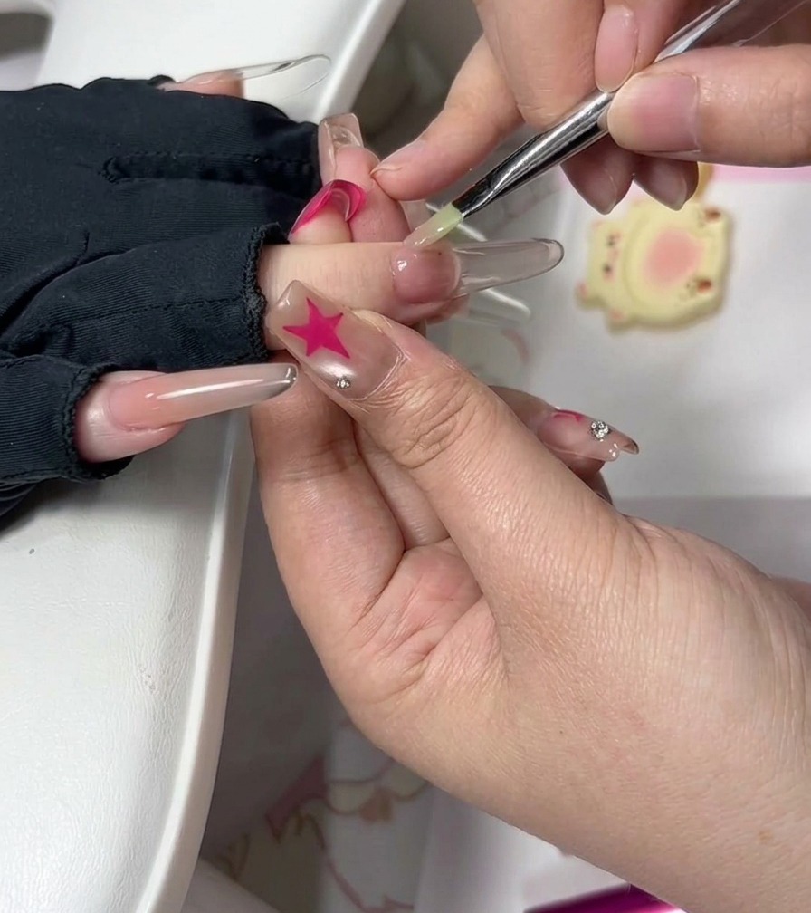 Unonicotecnica utilizza un pennellino per levigare accuratamente il gel vicino alle cuticole su ununghia ricostruita.
