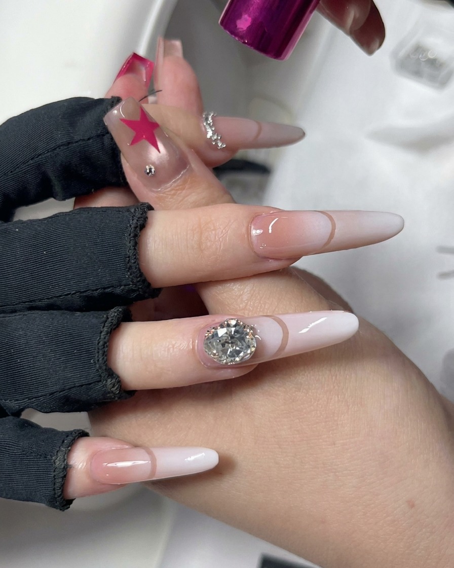 Una mano posizionata sotto una lampada UV/LED compatta di colore rosa con una nail art decorativa.