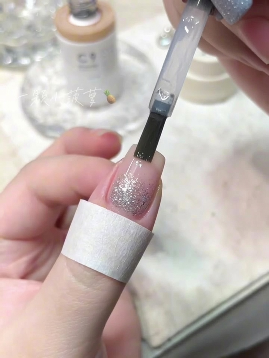 Un pennellino che applica un top coat trasparente su ununghia con glitter diamante.