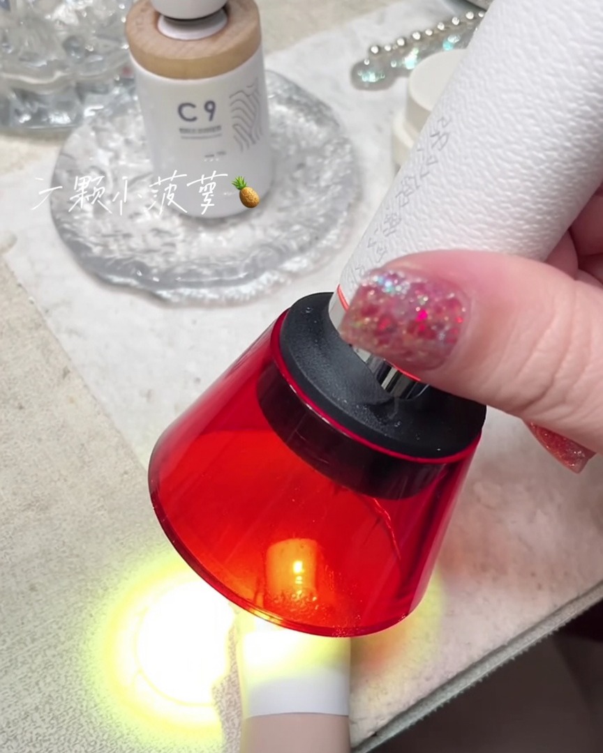 Una mini lampada UV rossa portatile che polimerizza ununghia su un dito.
