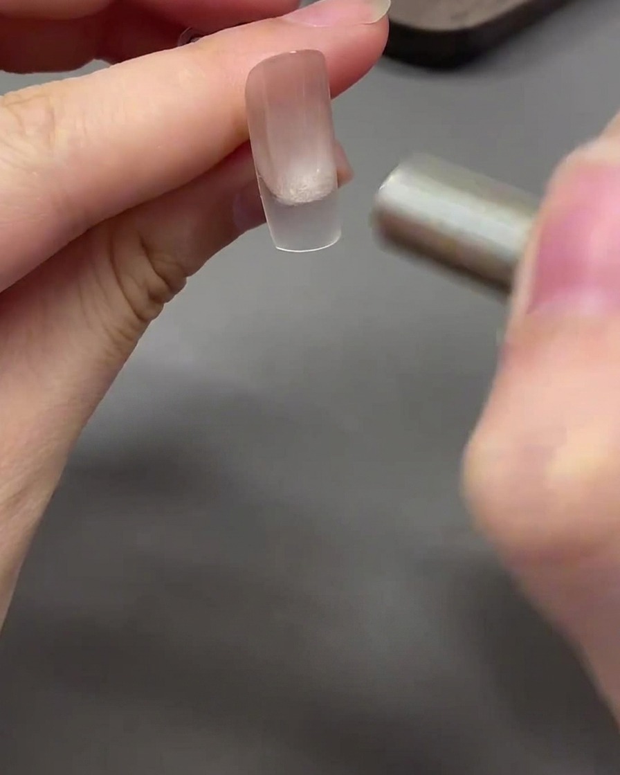 Un magnete che si muove con un movimento curvo attorno alla punta dellunghia per modellare il gel cat eye in un effetto perla di vetro.