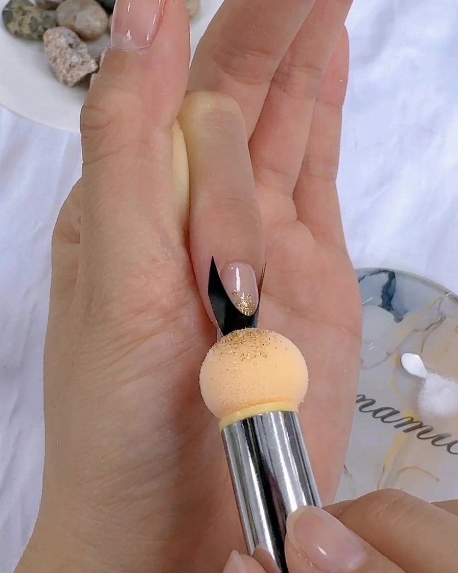 Una spugnetta da trucco picchietta il gel colorato su ununghia vicino alladesivo per french.