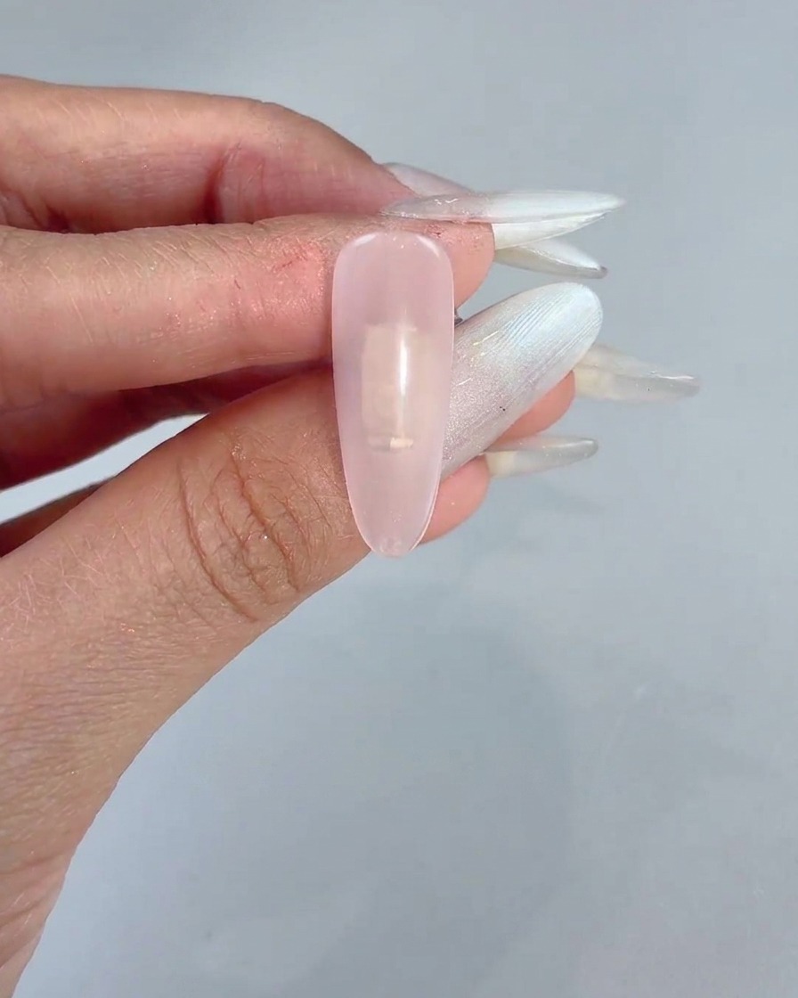 Una spugnetta che tampona delicatamente del gel rosa al centro di ununghia trasparente preparata per la manicure.