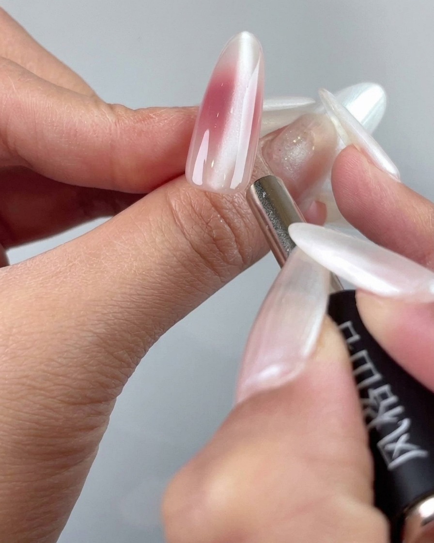 La punta di uno strumento magnetico di precisione che rifinisce le particelle cat-eye vicino alla zona delle cuticole di ununghia.