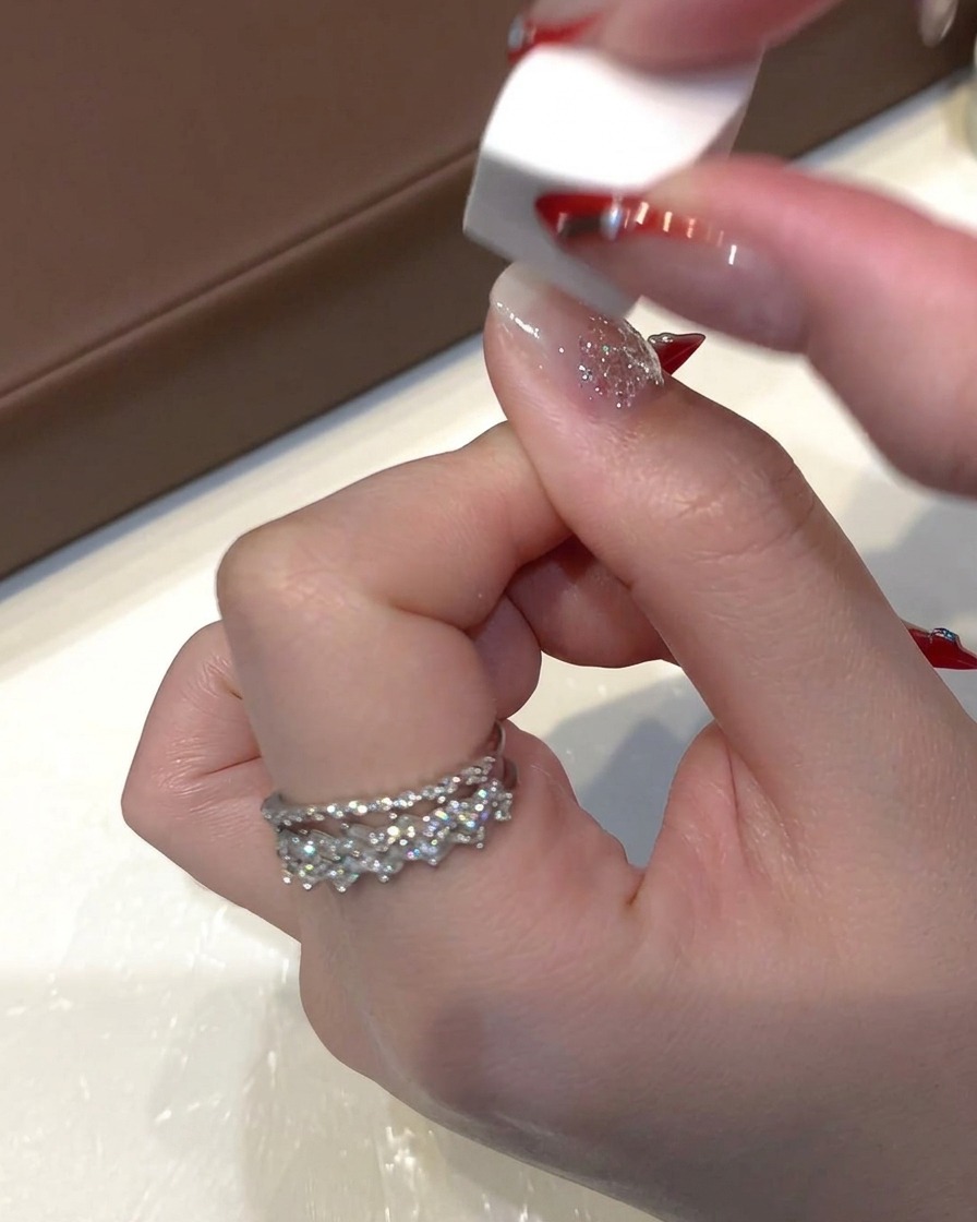 Una piccola spugnetta rettangolare bianca tampona leggermente il gel con paillettes fresco sullunghia per appiattire i glitter.
