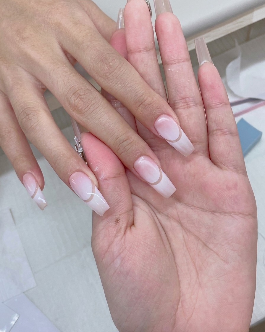 Un pennellino per gel applica un top coat trasparente e lucido su un design per unghie sfumato finito.