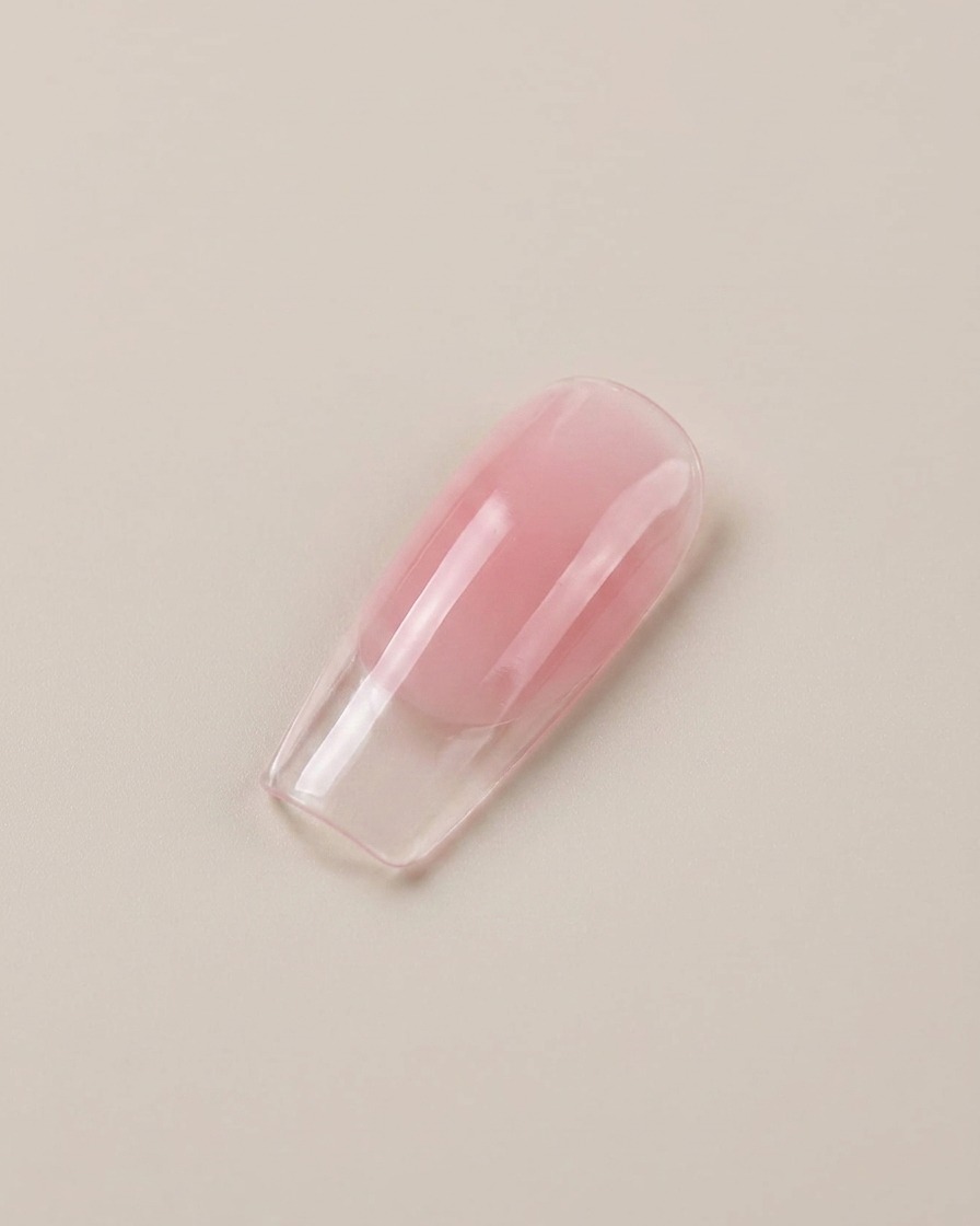 Un primo piano di una tip per unghie finte lucida e rosa traslucida.