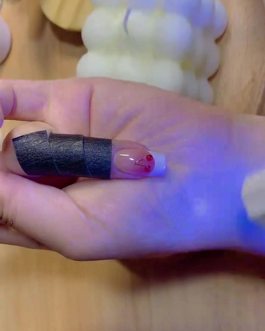 Un pennello fine riempie il colore bianco solido di una punta da manicure French su ununghia sfumata.