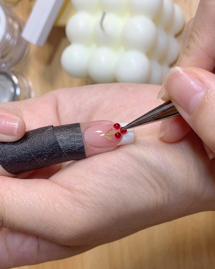 Un paio di pinzette posizionano due piccole sfere di gel 3D trasparenti sulla superficie di ununghia con manicure French.