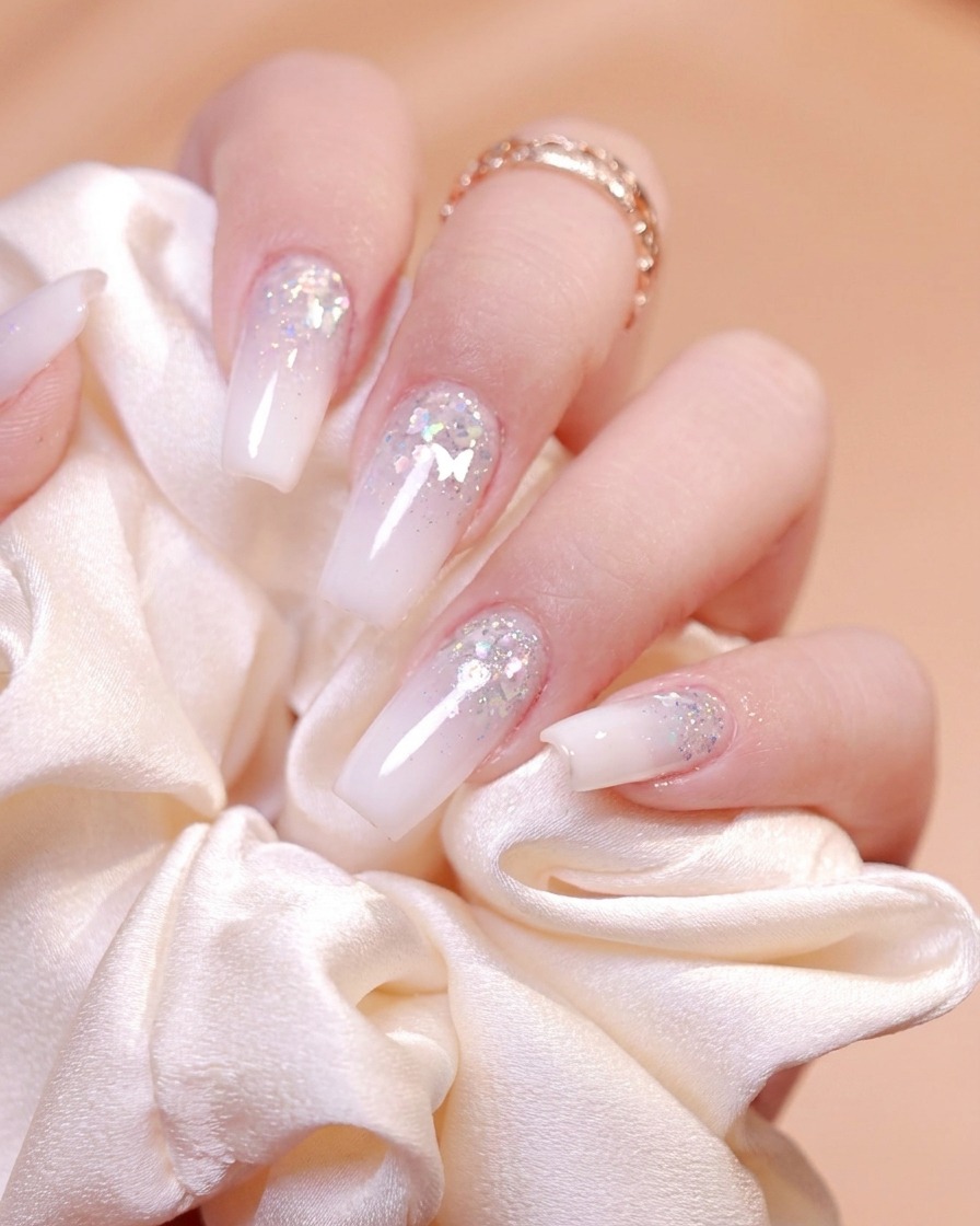 Un pennello fine per unghie che preleva gel glitterato argento da un piccolo contenitore nero.