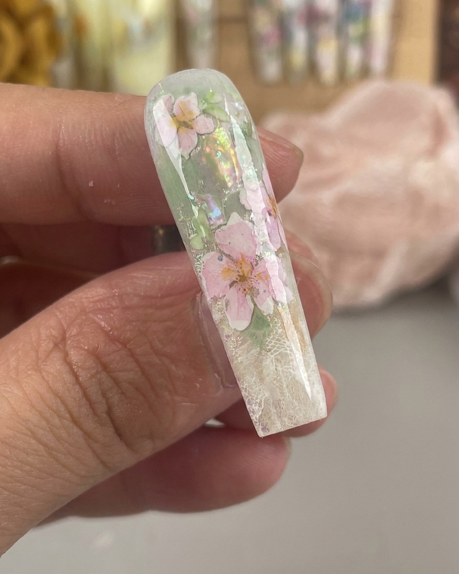 Ununghia lucida e incapsulata che mostra fiori ad acquerello rosa e gialli sigillati sotto un denso strato di gel trasparente.