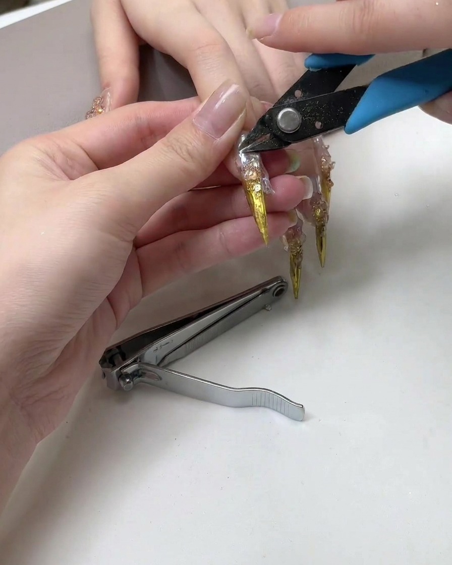 Tagliaunghie che tagliano la punta affilata di una lunga estensione metallica per unghie.