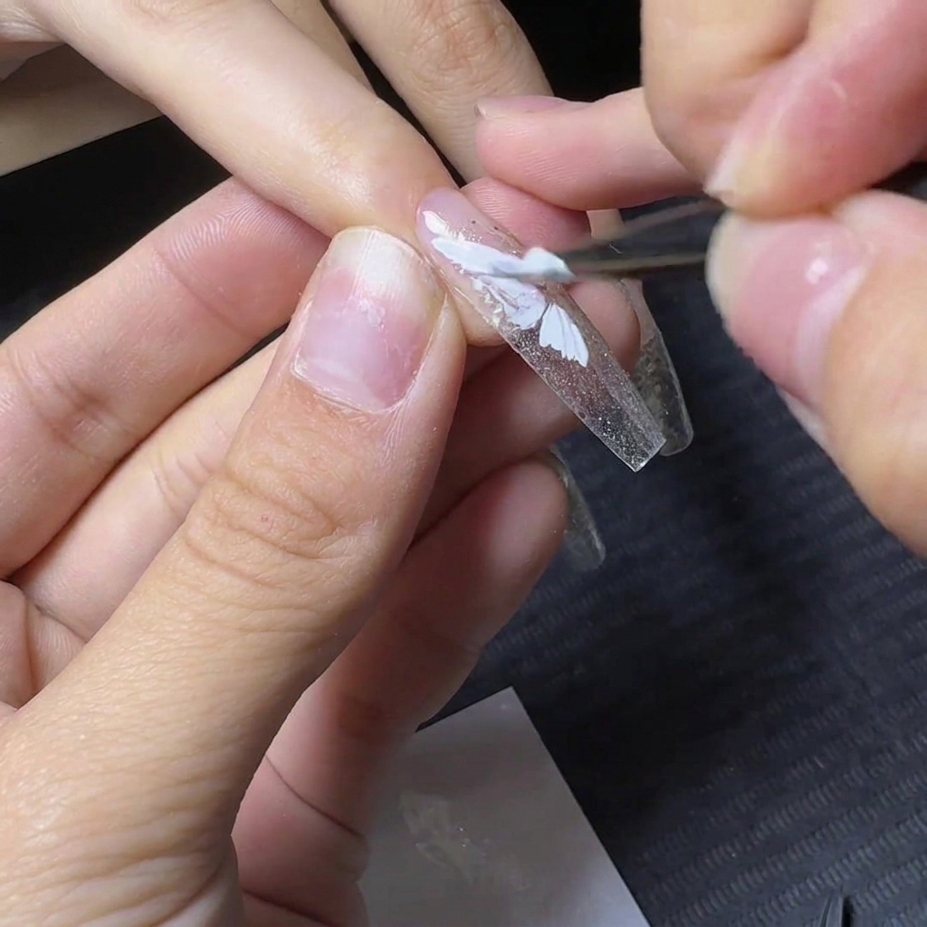 Un pennello da dettaglio che riempie la sezione inferiore del design dellala di farfalla in gel bianco.