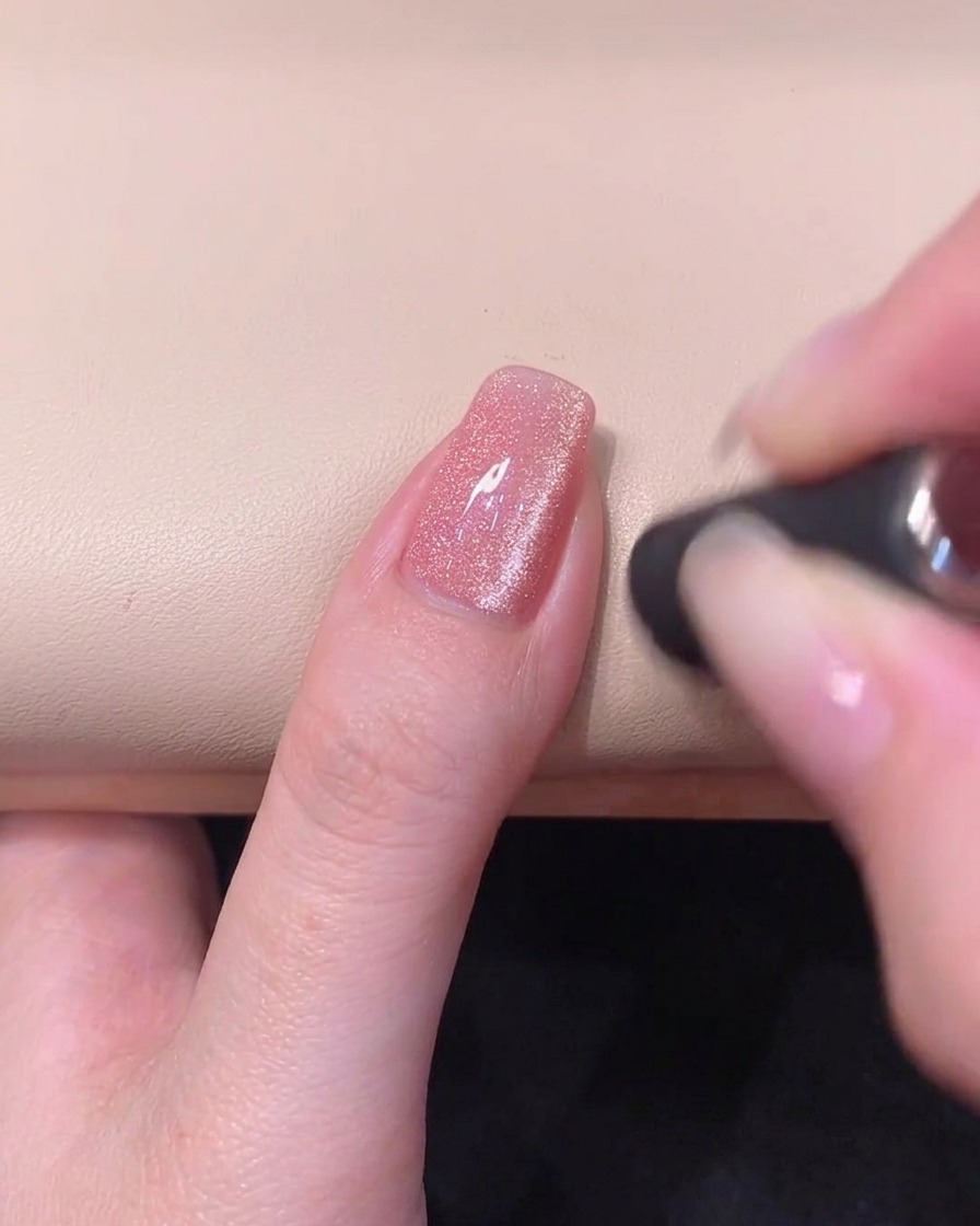 Un magnete cilindrico tenuto orizzontalmente attraverso la punta del margine libero dellunghia per formare una brillante banda cat-eye.