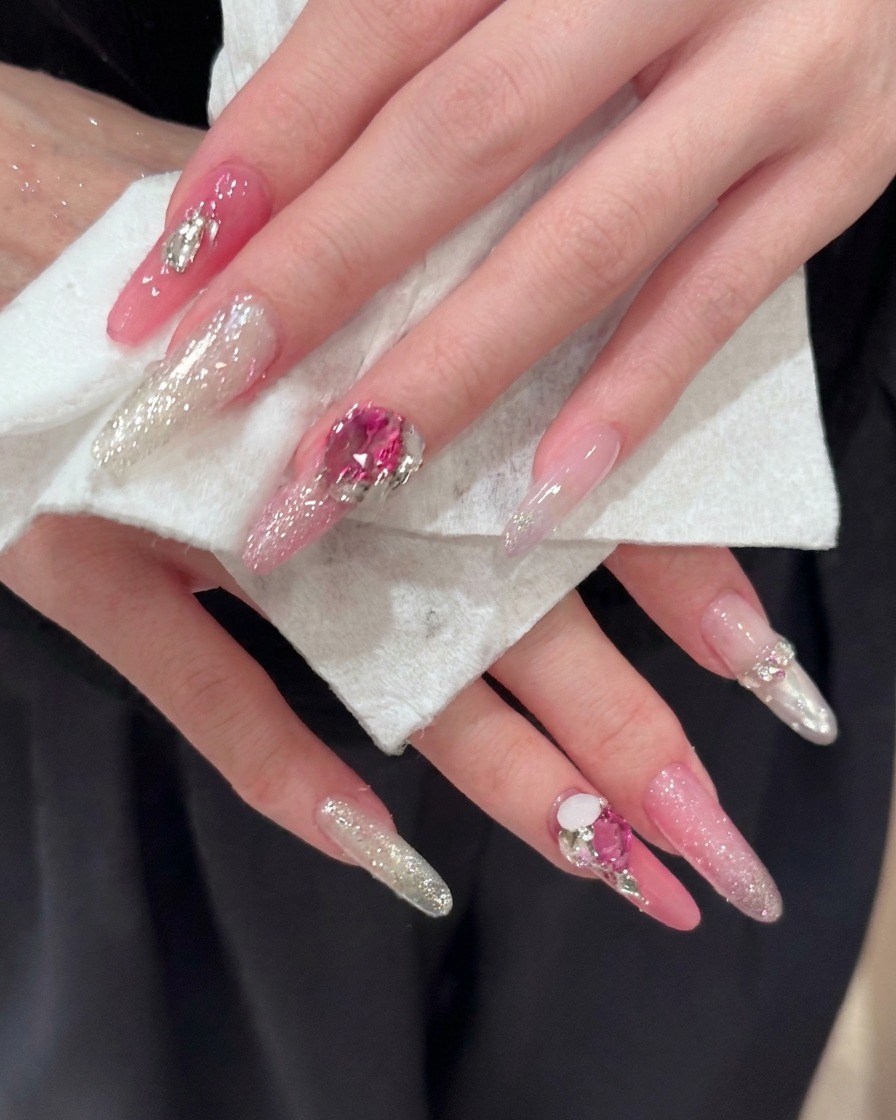 Un primo piano di unghie lunghe a mandorla che mettono in risalto dettagliati riflessi glitterati rosa e argento.