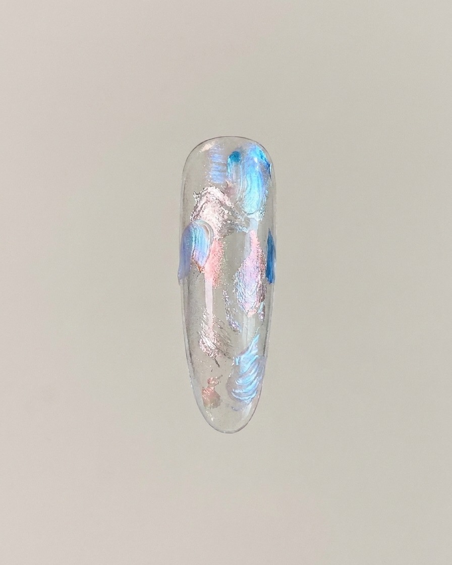 Una tip per unghie che mostra il gel cat eye magnetizzato in un effetto sfera di vetro centrale luminoso.
