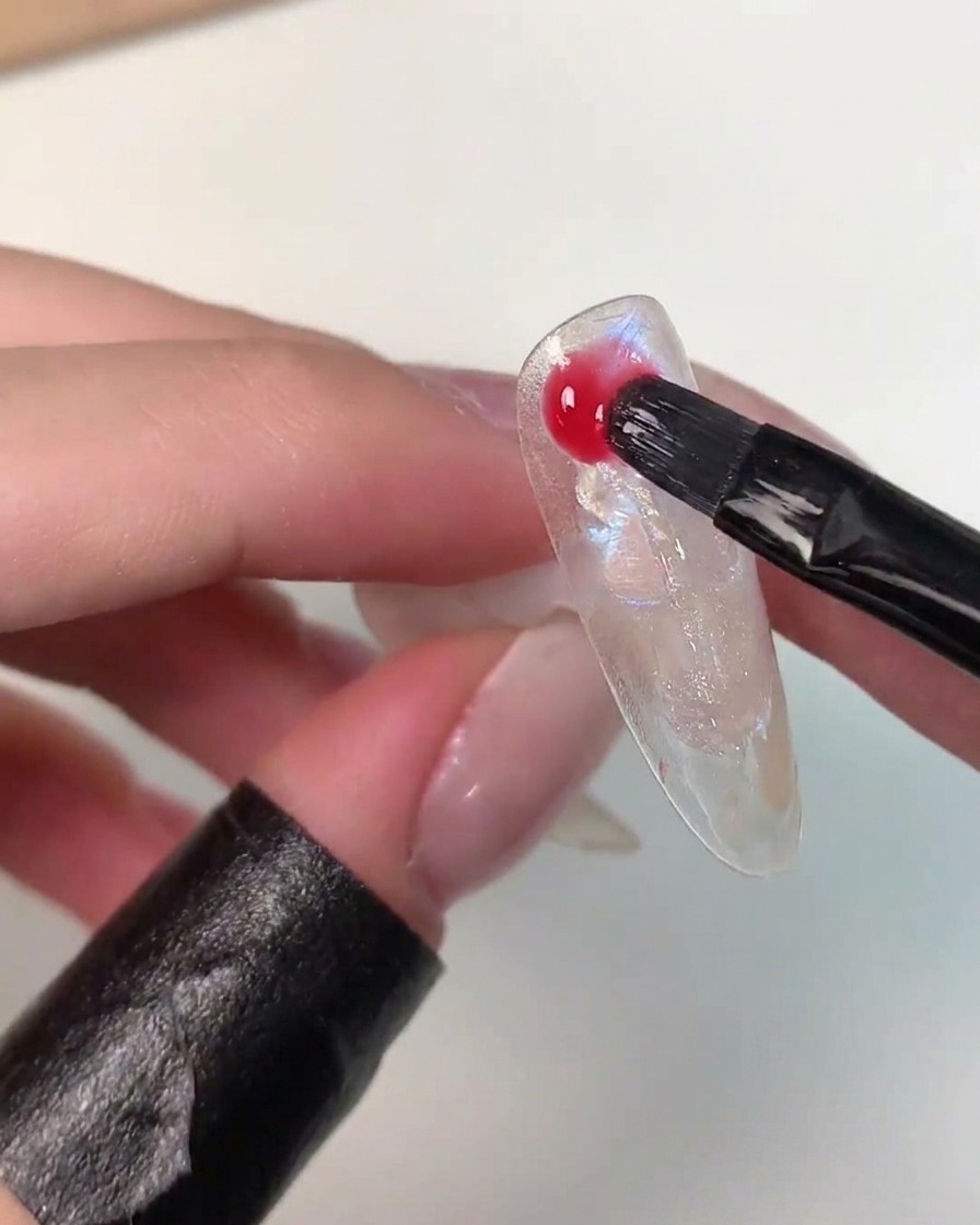 Un pennello che applica il vivace gel colore Eiko Esaka in modo casuale sulla superficie della nail art.