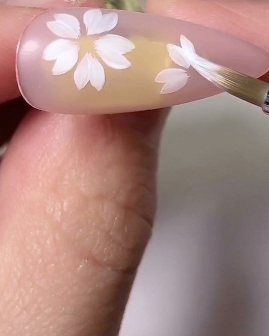 Un pennello che sfuma le tonalità rosa e bianche sui petali dei fiori di ciliegio per aggiungere profondità.