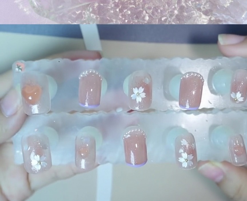 Primo piano di una piccola perlina dacciaio posizionata al centro di una nail art floreale.