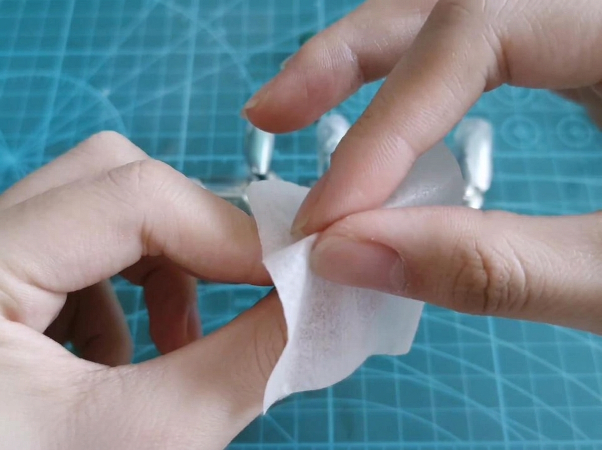Una salvietta imbevuta di alcol rimuove il residuo appiccicoso da una tip in gel polimerizzata.