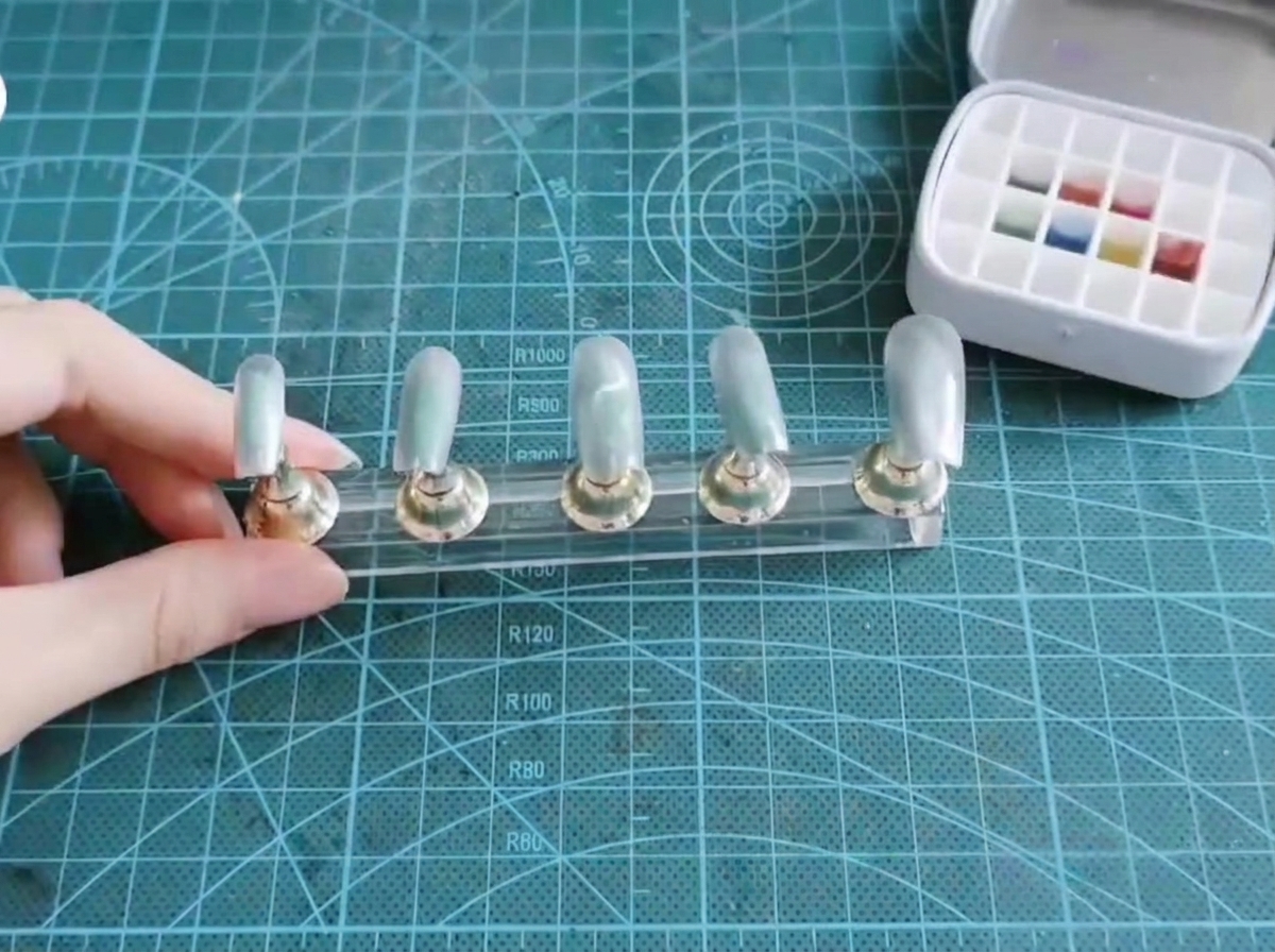 Un pennello piatto preleva pigmenti blu e viola da una palette di gel multi-colore.