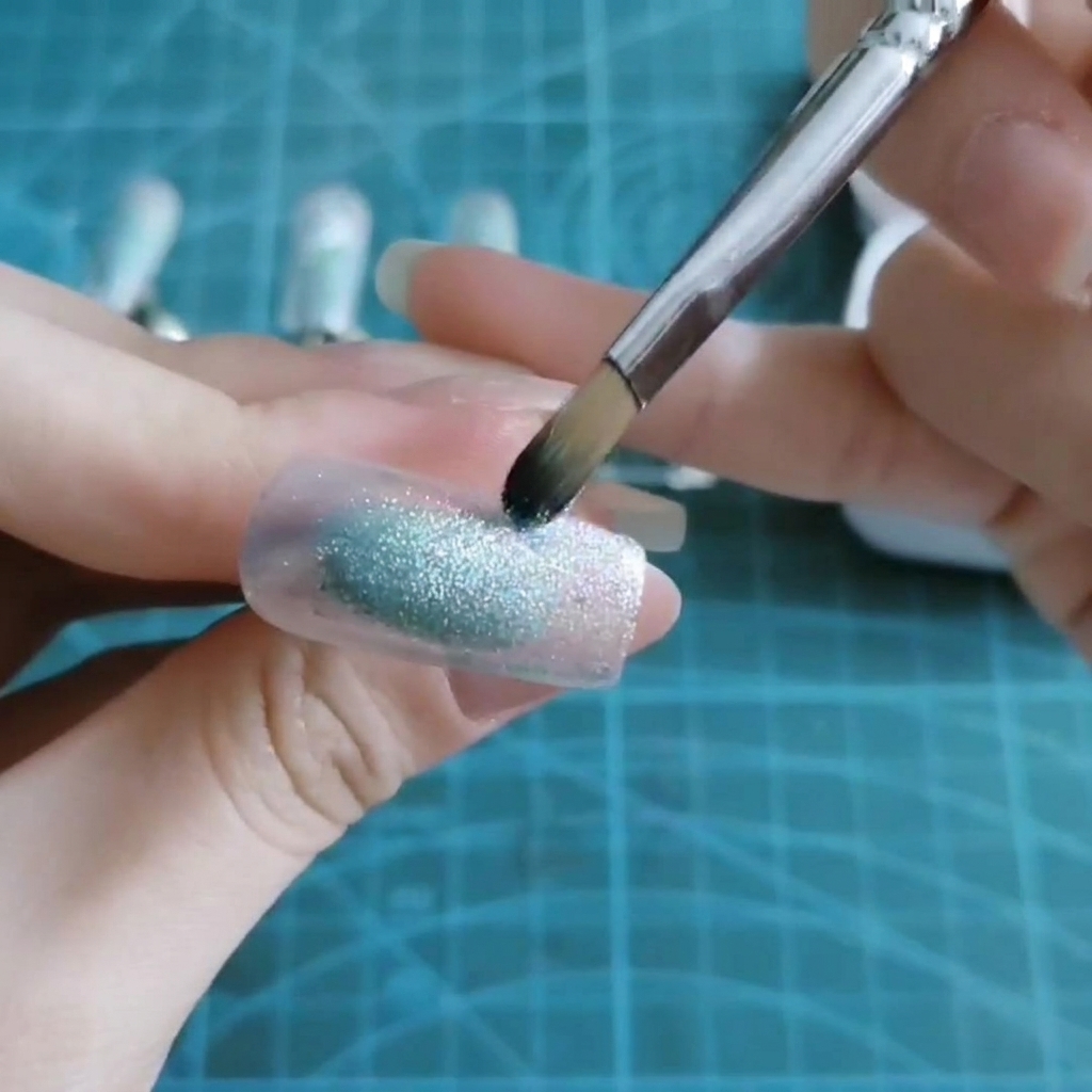 Un pennello tampona del gel blu traslucido al centro di una tip.