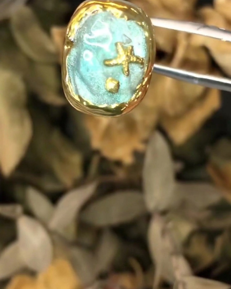 Un paio di pinzette che tengono il pezzo di nail art oceanico texturizzato durante lapplicazione dello strato finale.