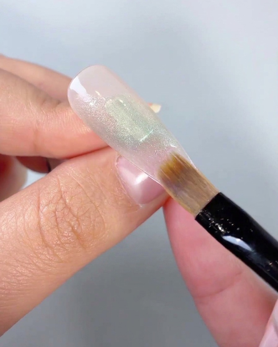 Primo piano di un pennello morbido che sfuma i bordi di un blocco di colore in gel verde su una tip.