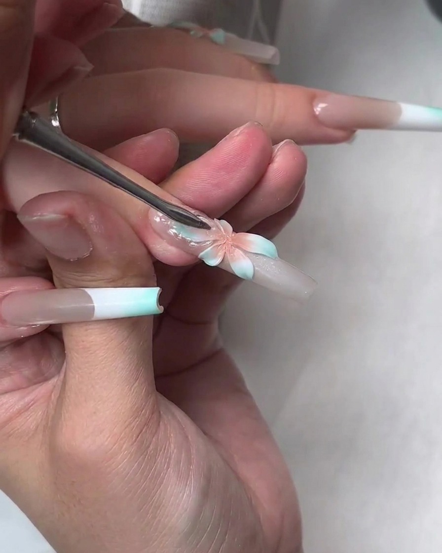 Uno strumento preme uno strato di gel costruttore morbido e trasparente sopra il fiore dipinto per creare petali traslucidi più grandi.