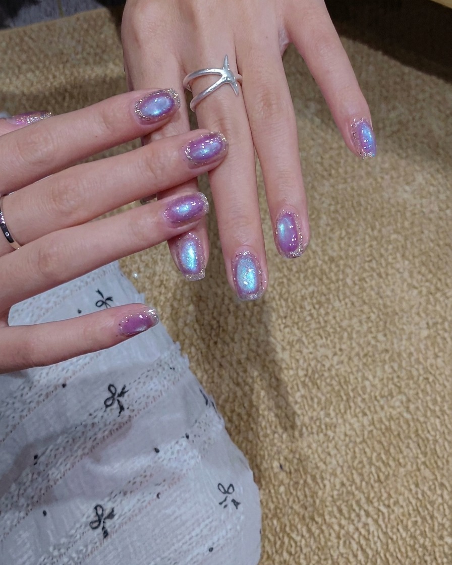 Un pennello che applica uno strato di smalto gel cat eye blu-viola brillante su ununghia.
