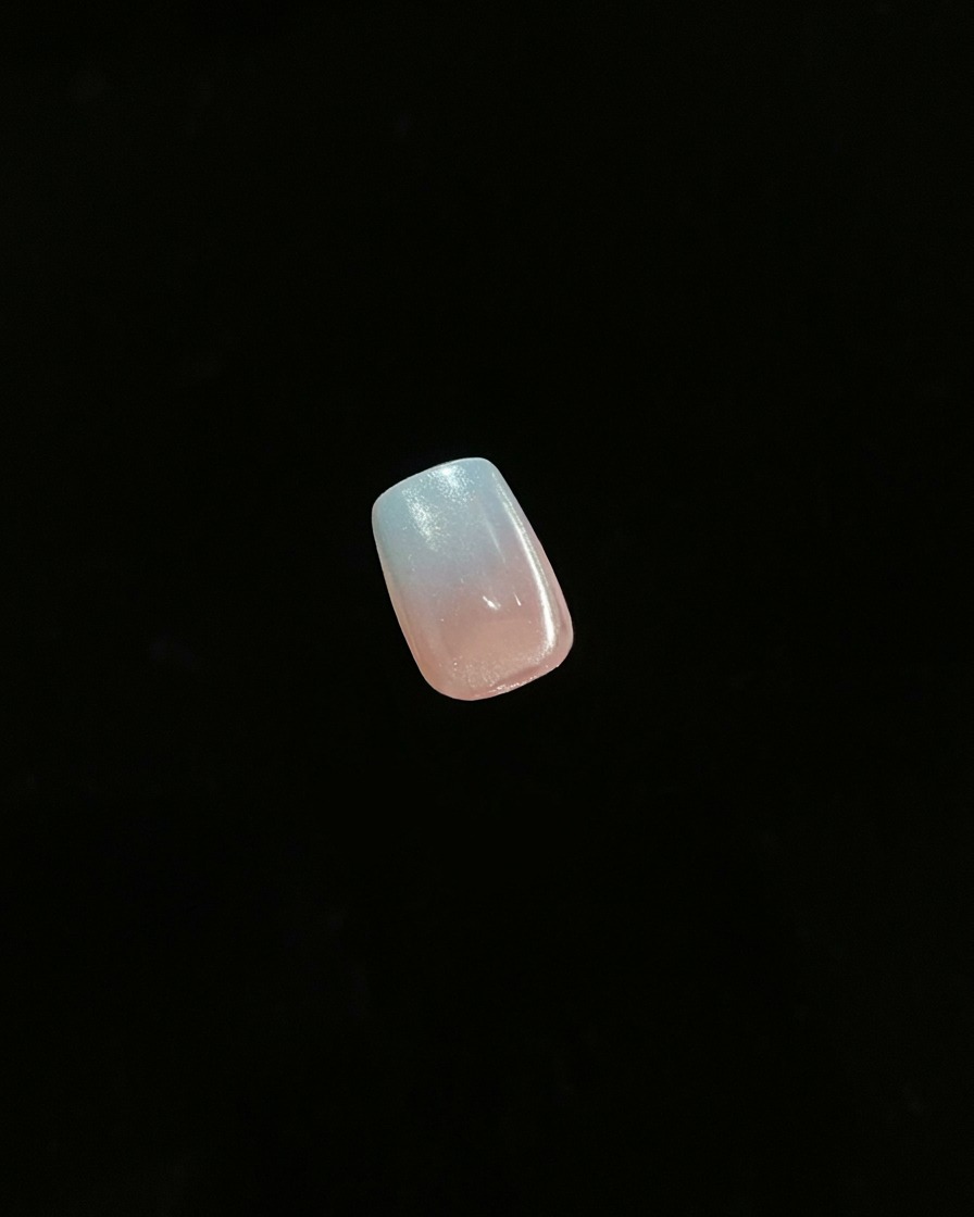 Primo piano di una singola unghia finita che mostra un effetto ombré sfumato su sfondo scuro.