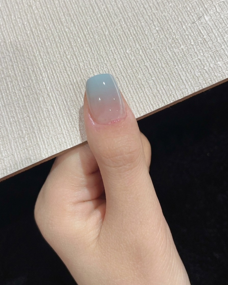 Un pollice posizionato sotto una lampada UV LED portatile durante la fase finale di polimerizzazione del top coat.