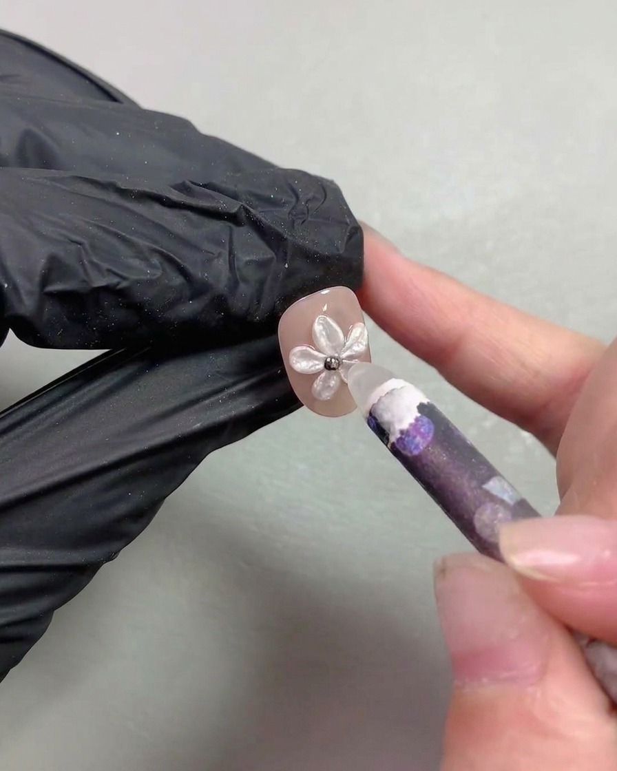 Uno strumento raccoglitore a cera che posiziona minuscole perline dacciaio metalliche al centro della nail art con fiore di perla.