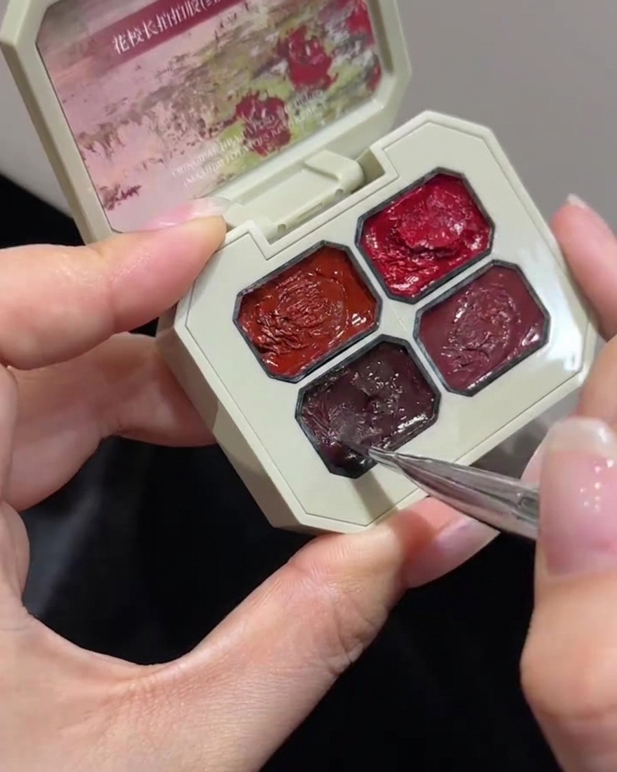 Un primo piano di un pennello fine per nail art che si immerge in uno scomparto specifico di una tavolozza di gel tamponato color rosa.