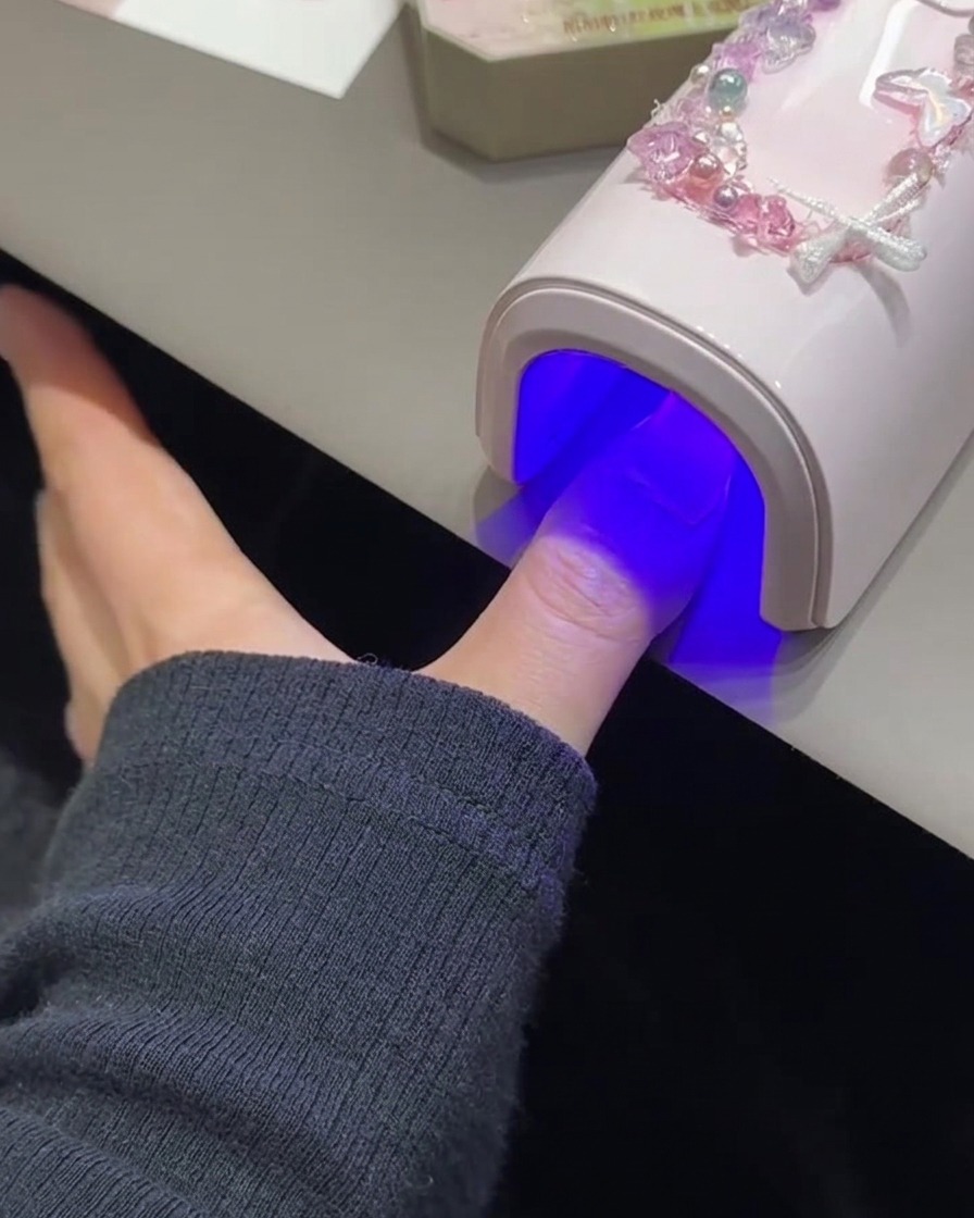 Ununghia in fase di polimerizzazione sotto una lampada UV/LED rosa.