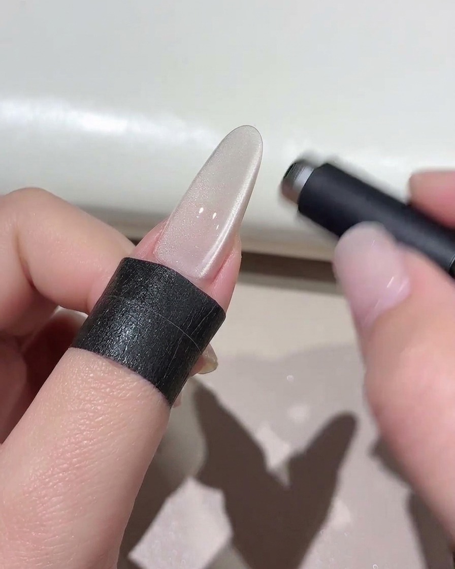 Un magnete cilindrico che si libra su ununghia cat-eye lucida per modellare leffetto di luce.