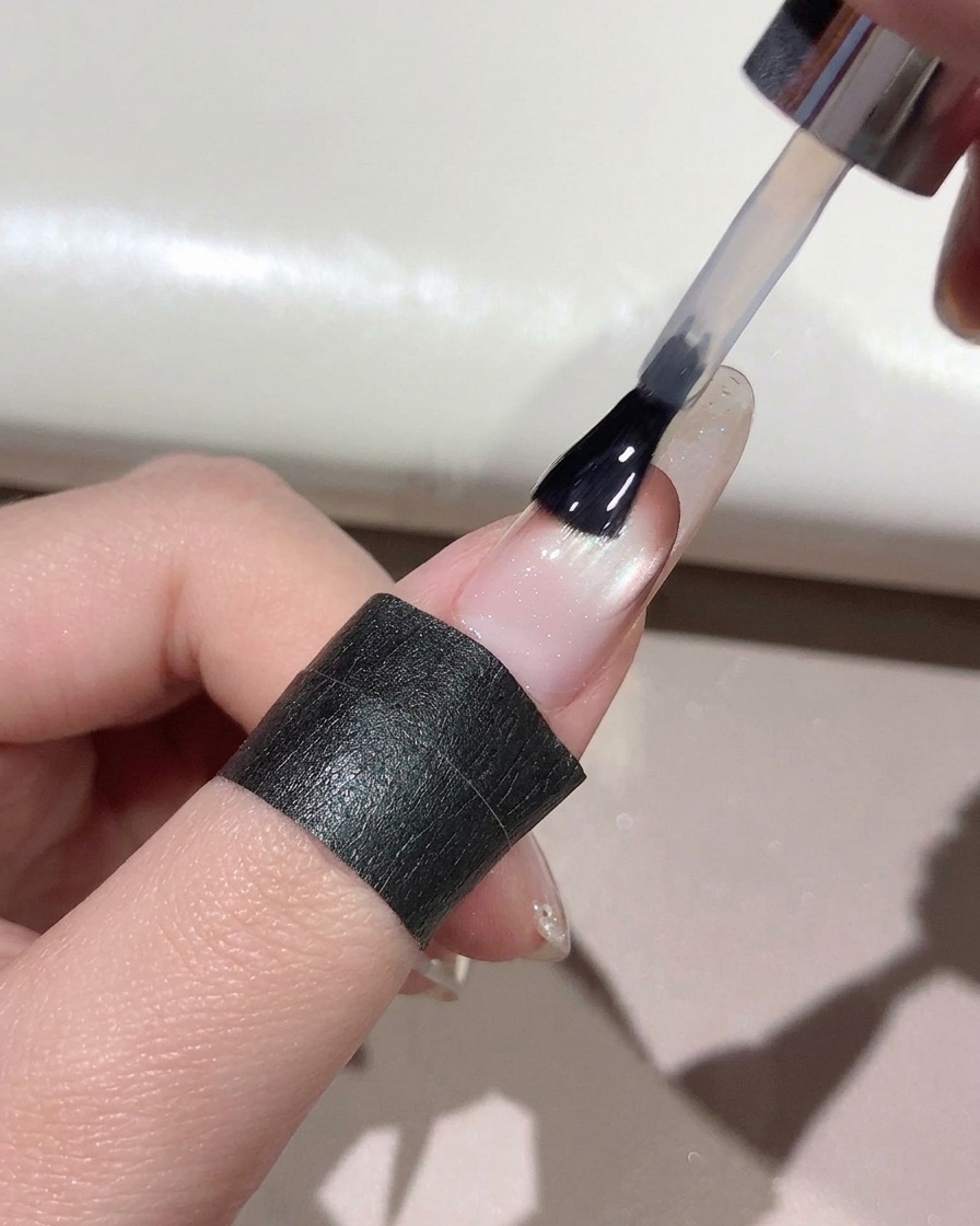 Un pennello che applica il top coat trasparente su tutta la superficie di ununghia curata.