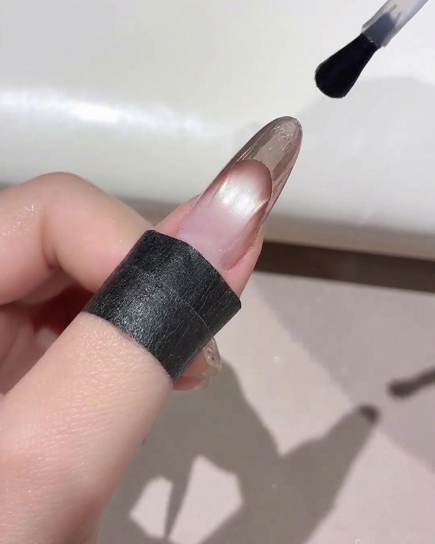 Un pennello per unghie che applica un top coat trasparente sulla punta di una manicure French finita.