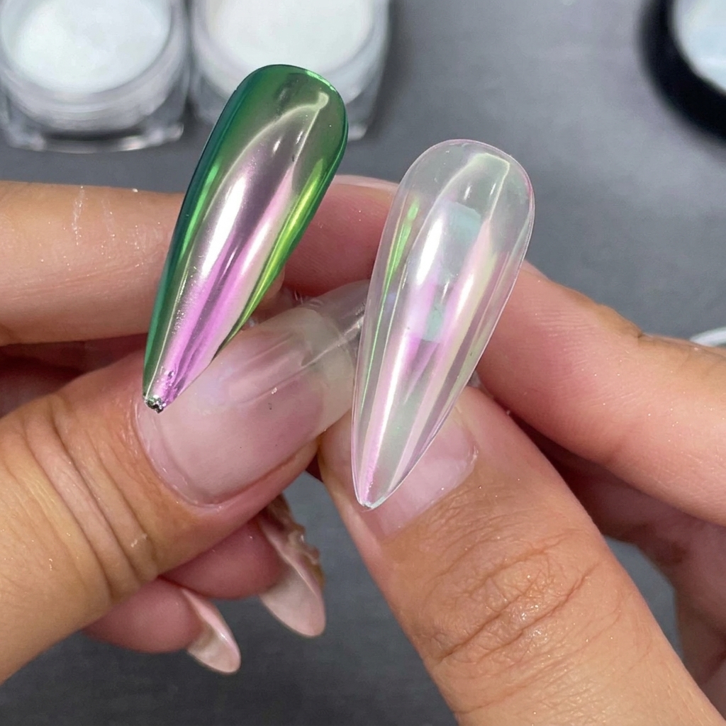 Due punte per unghie a stiletto finite tenute fianco a fianco, una con base trasparente e una con base nera che mostra una sfumatura verde-viola.