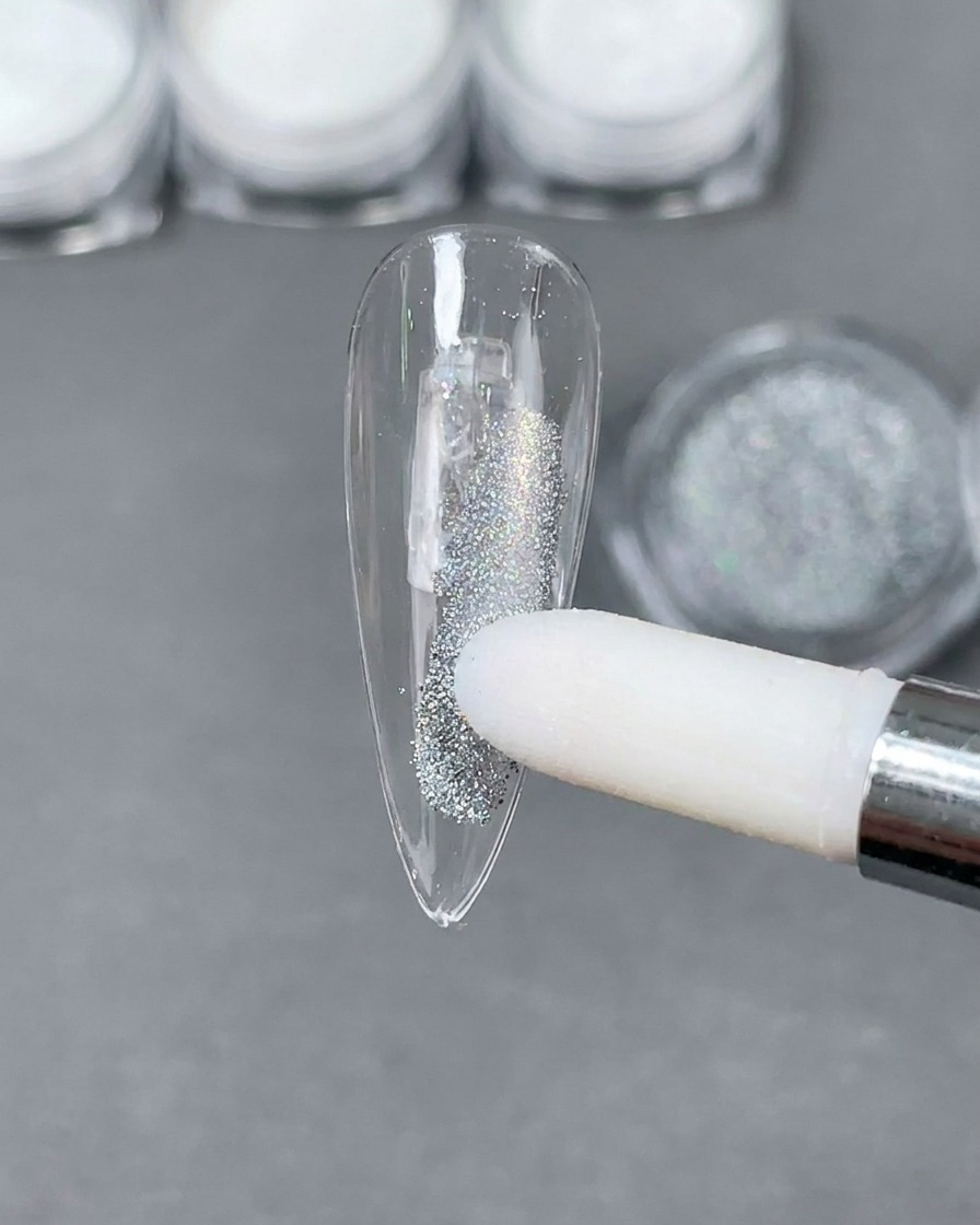 Un applicatore in spugna che posiziona la polvere olografica Laser argentata su una punta per unghie a stiletto trasparente.