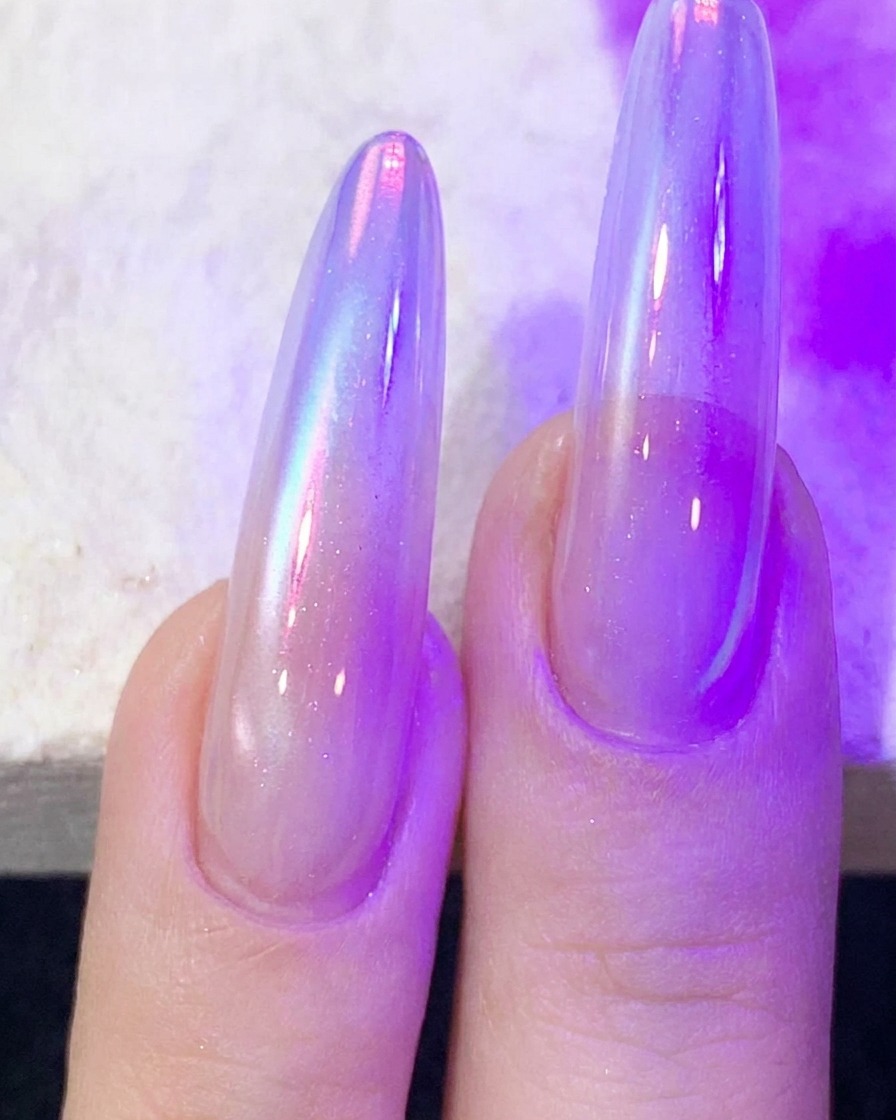 Dita con gel per unghie cat-eye in fase di polimerizzazione sotto una lampada per unghie UV/LED viola.