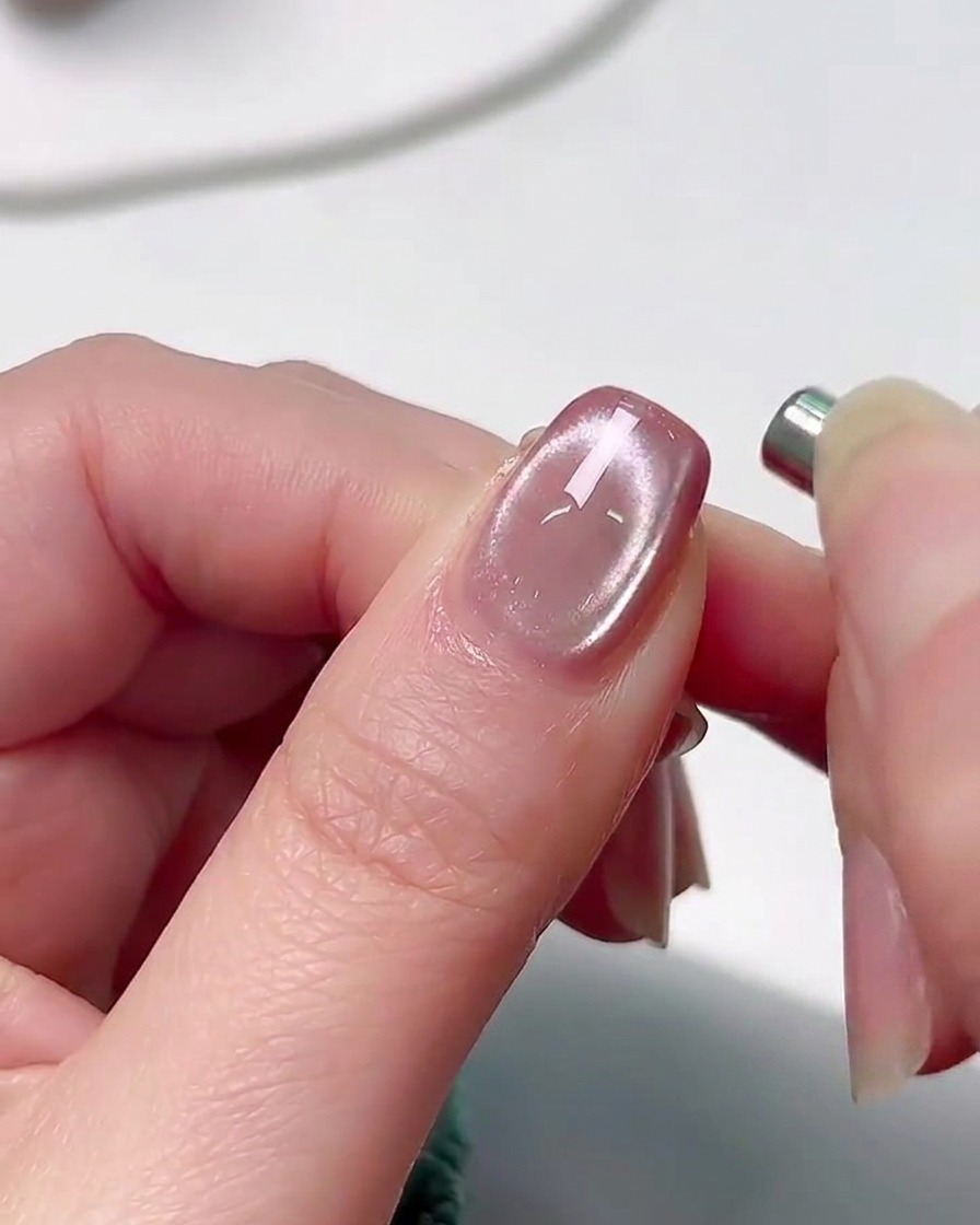 Una mano posta allinterno di una lampada professionale per polimerizzazione unghie UV con un morbido chiarore rosa che illumina le dita.
