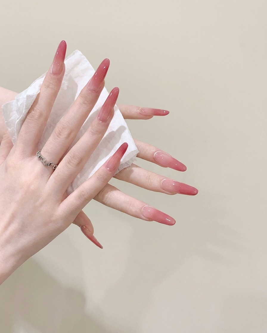 Una vista in primo piano di un paio di mani che puliscono accuratamente unghie lunghe a stiletto con un fazzoletto bianco bagnato.